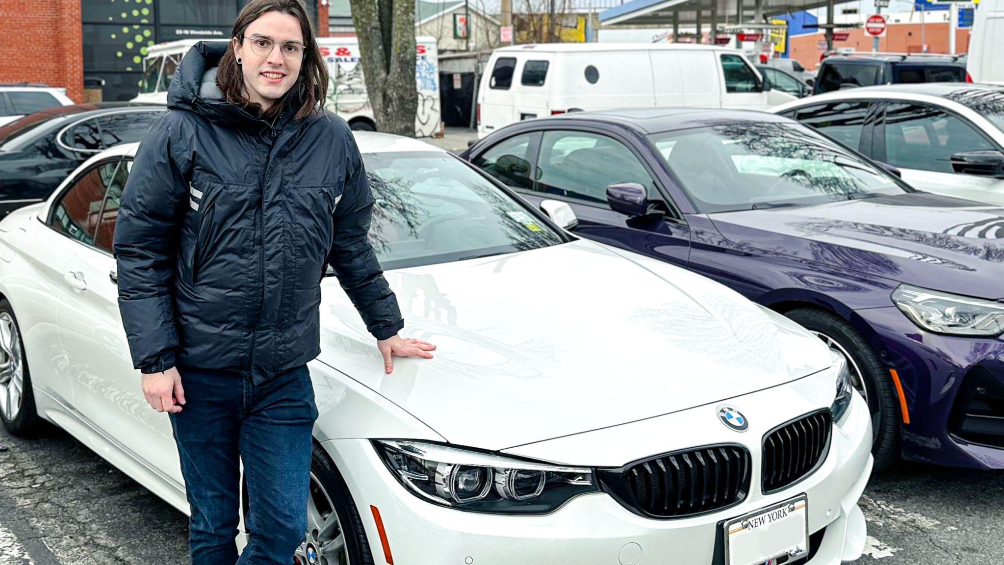 Acceleramota founder and NYCars & Coffee organizer Gabe Carey standing next to white 2018 BMW 430i with hand on hood