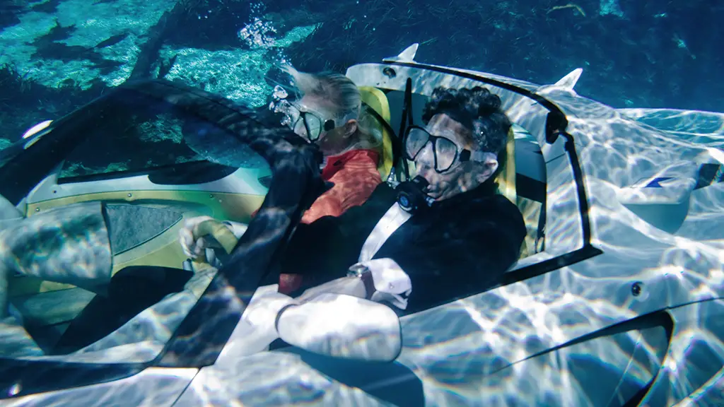 A promotional image for the sQuba submarine car, we see a guy in a tuxedo driving with a scuba mask on.