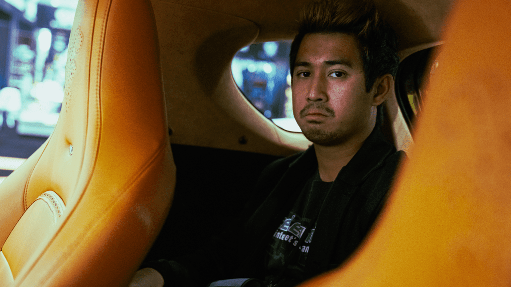 Jeric Jaleco acting stoic in the back of an Aston Martin Cygnet