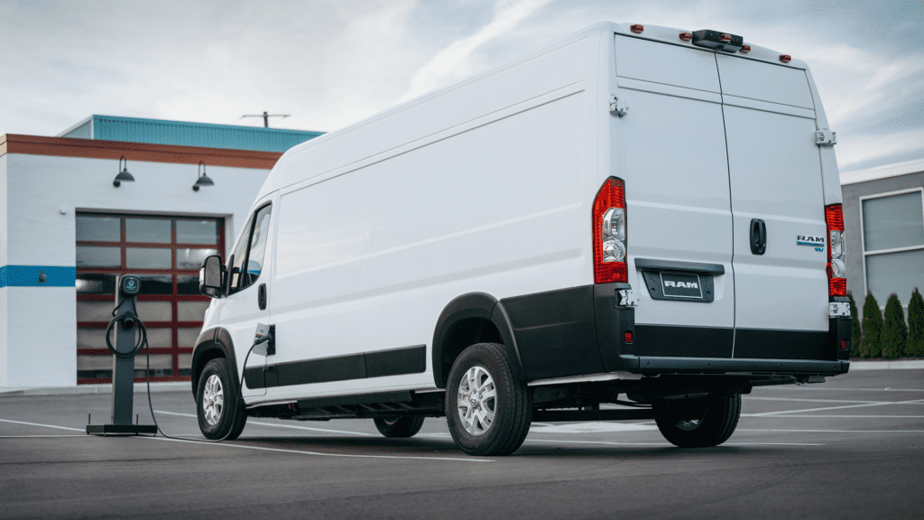 Ram ProMaster EV plugged in, charging in warehouse parking lot