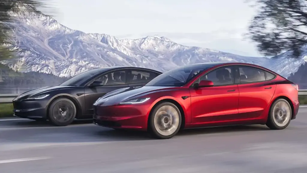 A red and a grey 2024 Tesla 3 are seen on a road.